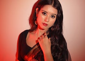 Portrait of a south Asian woman in a black saree with red lighting, showcasing traditional Indian fashion.